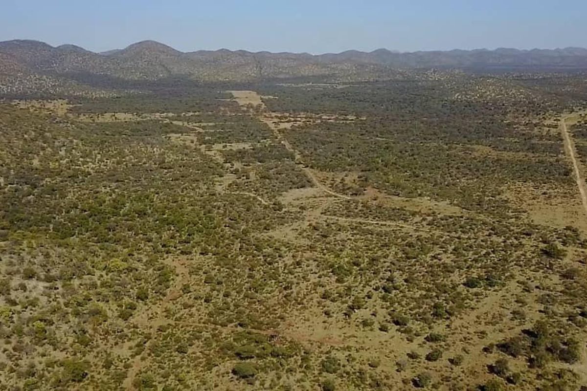 An expansive aerial view of the farm property, showcasing the vast natural landscape, rolling hills, and existing dirt access roads.