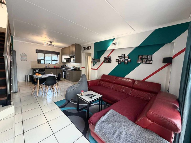 Open-plan living area featuring a kitchen with built-in cabinetry and tiled flooring, seamlessly connected to the lounge space.