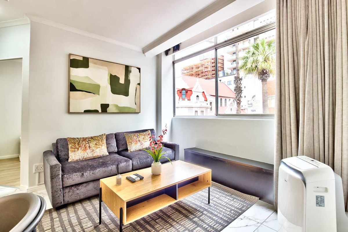 A bright and well-maintained living room featuring a large window with urban views and a built-in window ledge.