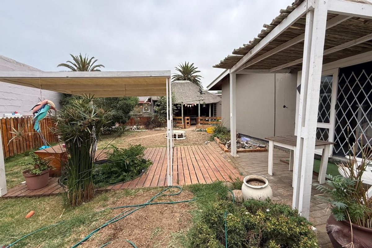 A rear garden featuring a paved patio area, timber decking, and a covered outdoor space, providing a functional area for outdoor living.