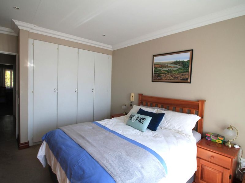 A well-maintained bedroom featuring neutral wall tones, built-in cupboards, and recessed ceiling lighting, offering a functional and comfortable living space.