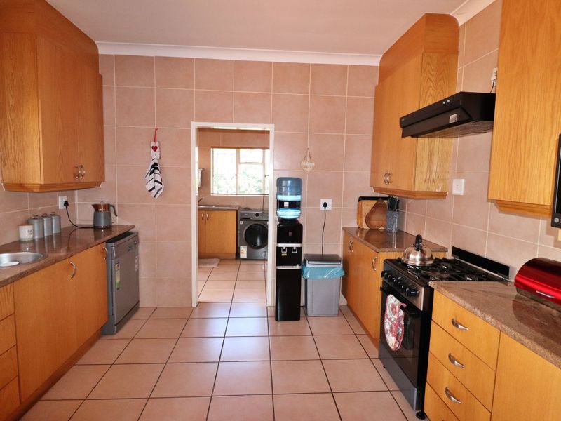A functional kitchen featuring wooden cabinetry, granite countertops, tiled walls and flooring, and a gas stove with an extractor fan.