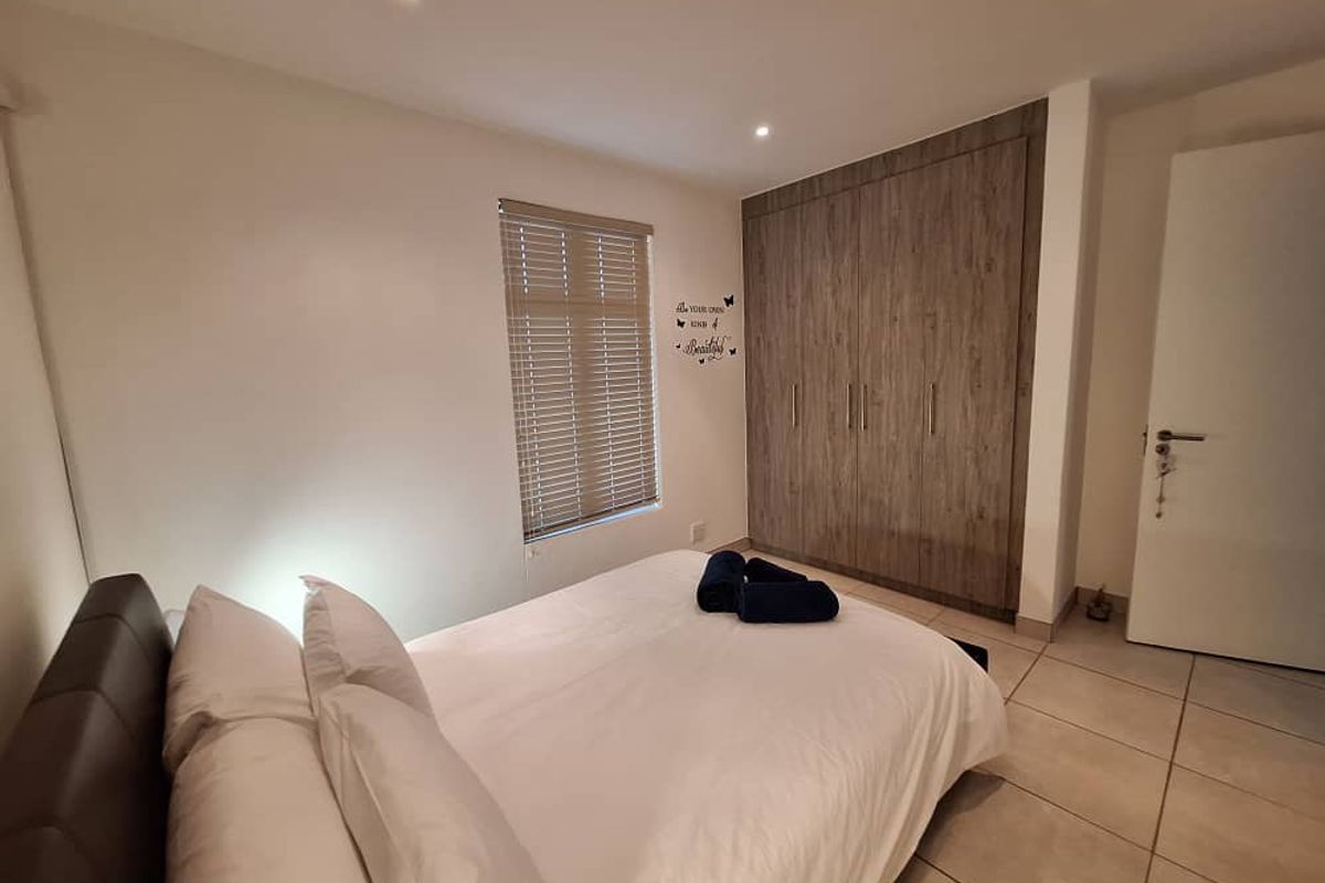 A well-maintained bedroom featuring built-in wooden cabinetry, tiled flooring, recessed ceiling lighting, and a window with fitted blinds.