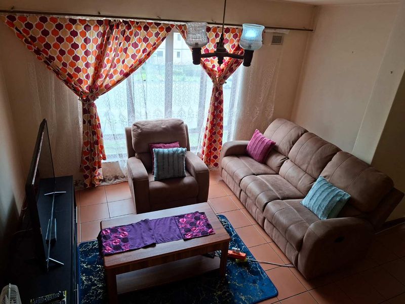 A living room featuring tiled flooring and a large window, providing a functional space for relaxation.