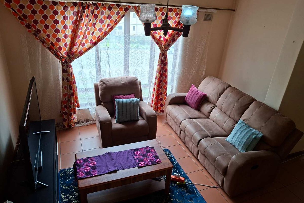 A living room featuring tiled flooring and a large window, providing a functional space for relaxation.