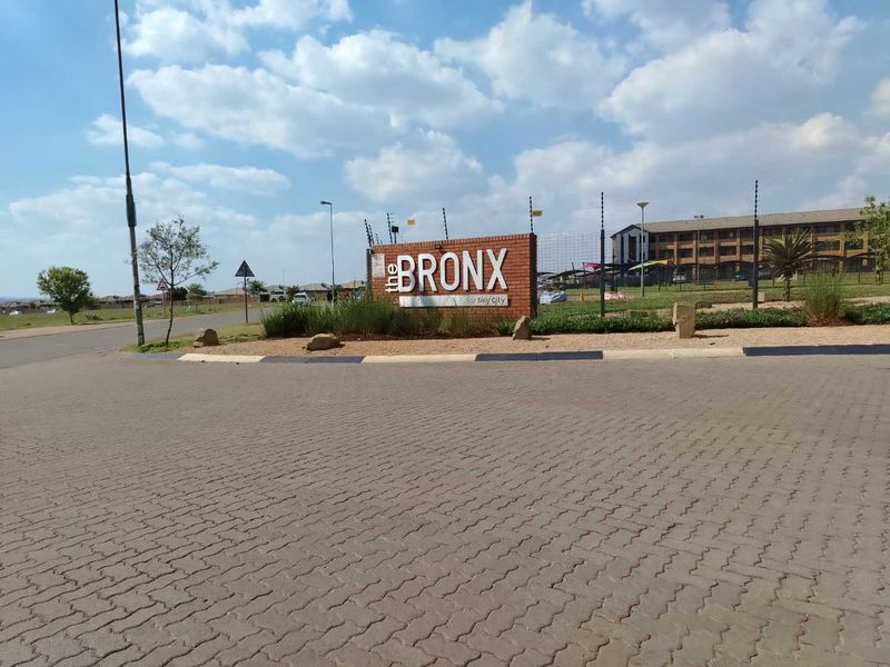 Entrance view of The Bronx at Sky City complex, featuring paved access, perimeter electric fencing, and clear signage.
