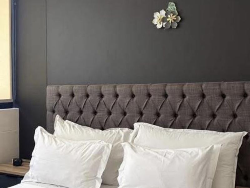 A bedroom featuring a dark accent wall and a modern pendant light fixture.