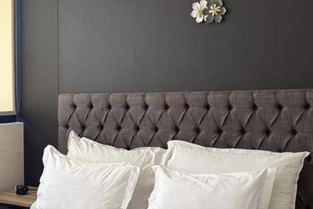 A bedroom featuring a dark accent wall and a modern pendant light fixture.