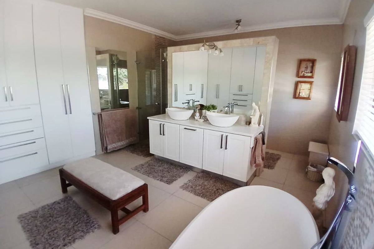 Spacious primary bathroom featuring a double vanity with vessel sinks, large built-in wardrobe cabinetry, and a freestanding bathtub.