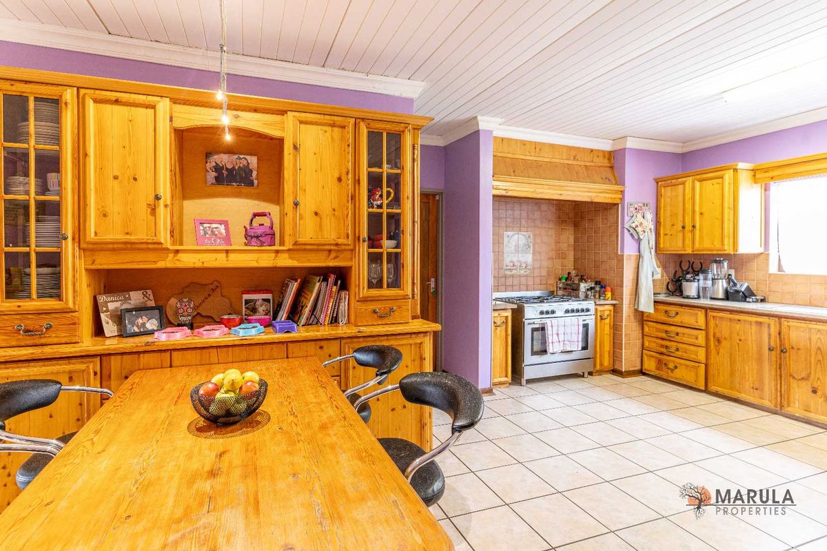 Spacious kitchen featuring extensive wooden cabinetry, a built-in stove with extractor hood, tiled flooring, and a dedicated dining area.