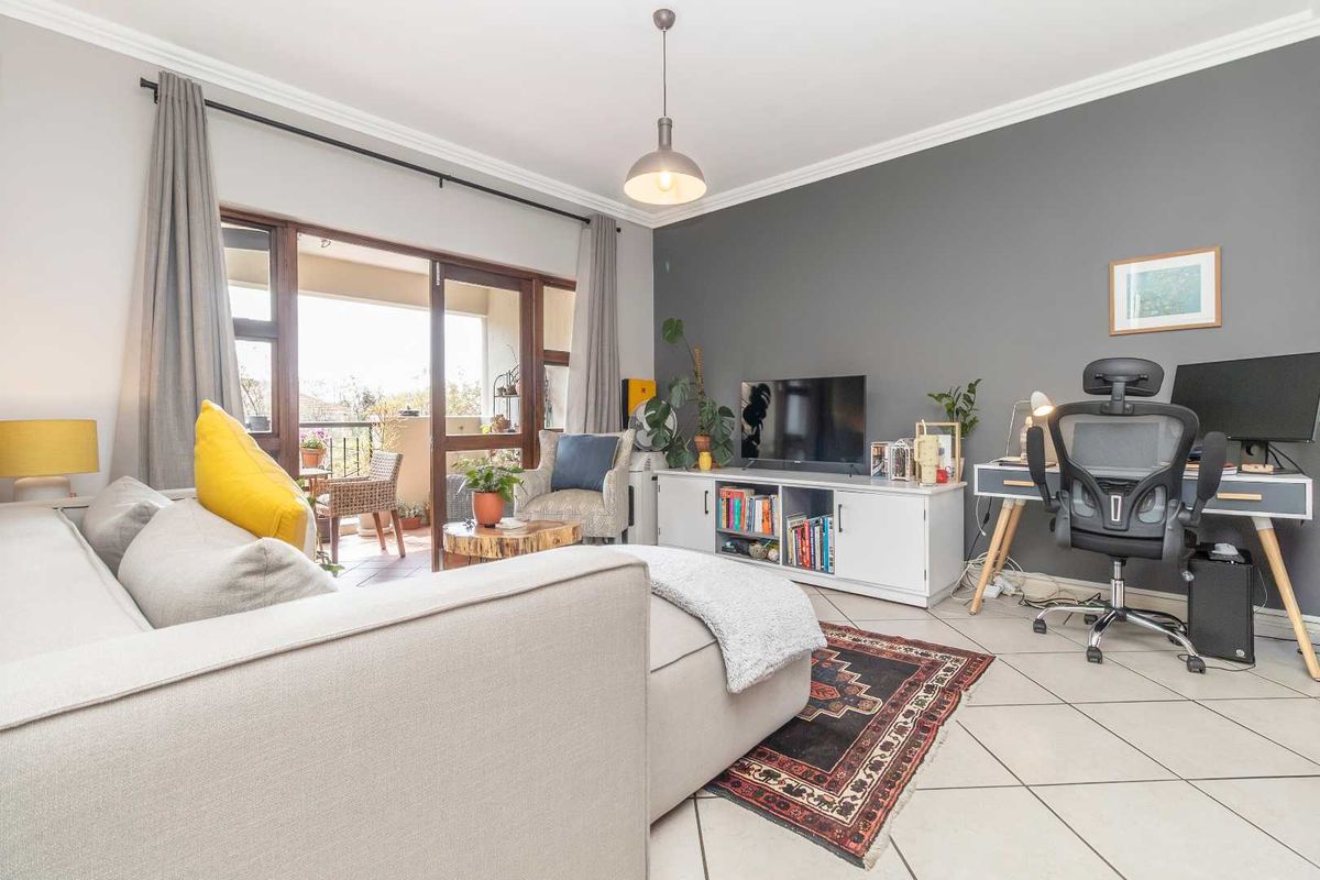A bright living room featuring tiled flooring, crown molding, and a sliding glass door providing access to an outdoor balcony area.