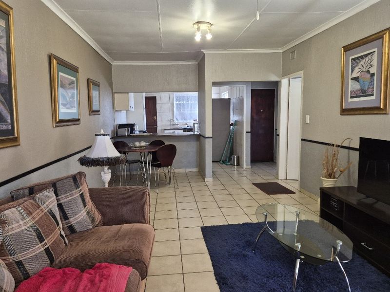 Open plan living and dining area featuring tiled flooring, a breakfast bar, and a functional kitchen layout.