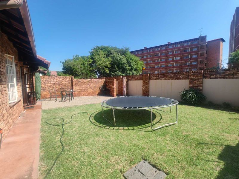A private rear garden featuring a paved patio area, established lawn, and secure brick boundary walls.