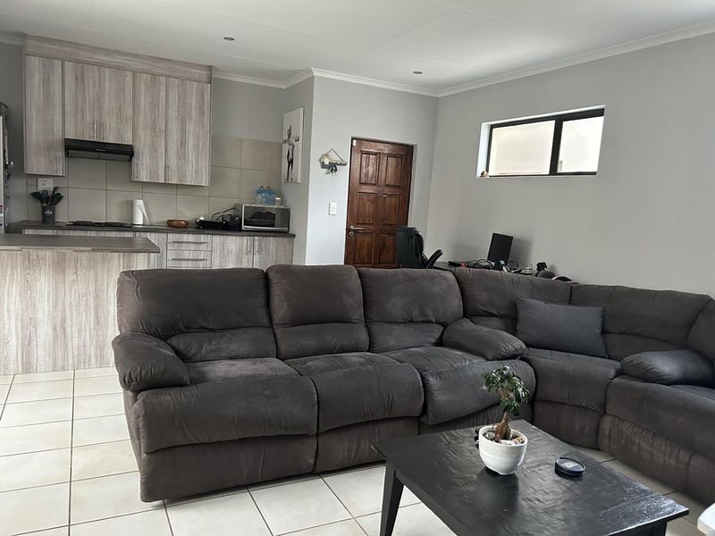 Open-plan living area featuring a modern kitchen with wood-look cabinetry, tiled floors, and recessed lighting, seamlessly connected to the lounge space.