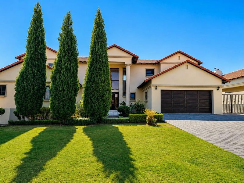 A well-maintained double-story residential home featuring a paved driveway, double garage, and manicured front garden with mature cypress trees.