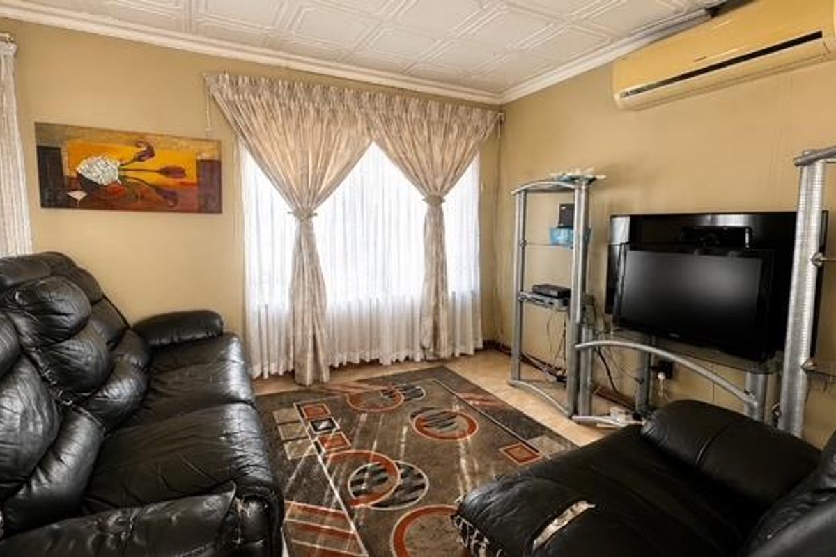 A living room featuring tiled flooring, a tiled ceiling, and a wall-mounted split-system air conditioning unit.