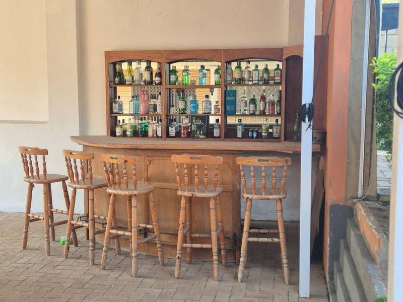 Outdoor bar area featuring a built-in wooden counter and integrated shelving with mirrored backing, situated on a paved patio.