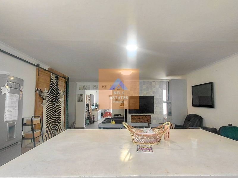 Spacious open-plan living area featuring a central kitchen island, a built-in fireplace with stone tiling, and a sliding barn door feature.