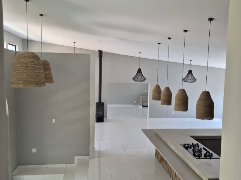 Spacious open-plan living area featuring a modern kitchen island with integrated gas hob, sleek tiled flooring, and a contemporary built-in fireplace.