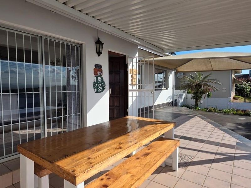 A covered outdoor patio area featuring tiled flooring, a corrugated metal roof, and direct access to the home through sliding glass doors.