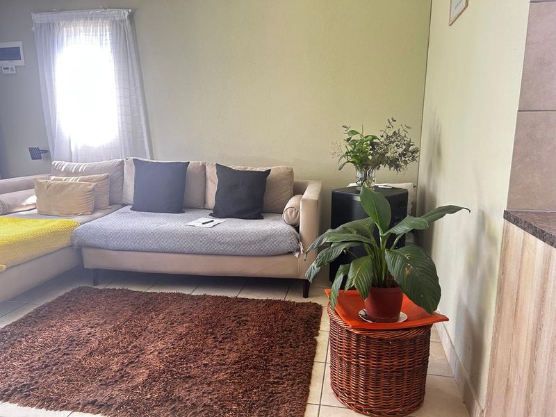 A living room area featuring neutral wall tones and tiled flooring, providing a functional space for relaxation.