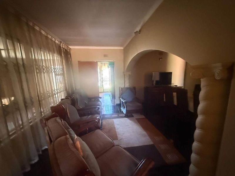 A living room featuring a decorative archway with a fluted column, tiled flooring, and coved ceiling details.