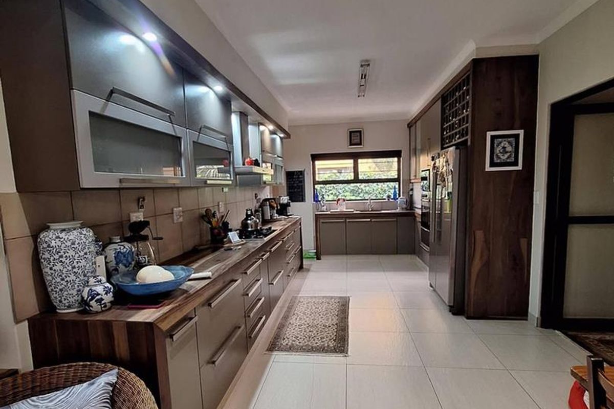 Modern galley-style kitchen featuring extensive built-in cabinetry, laminate countertops, tiled flooring, and integrated storage solutions with recessed lighting.