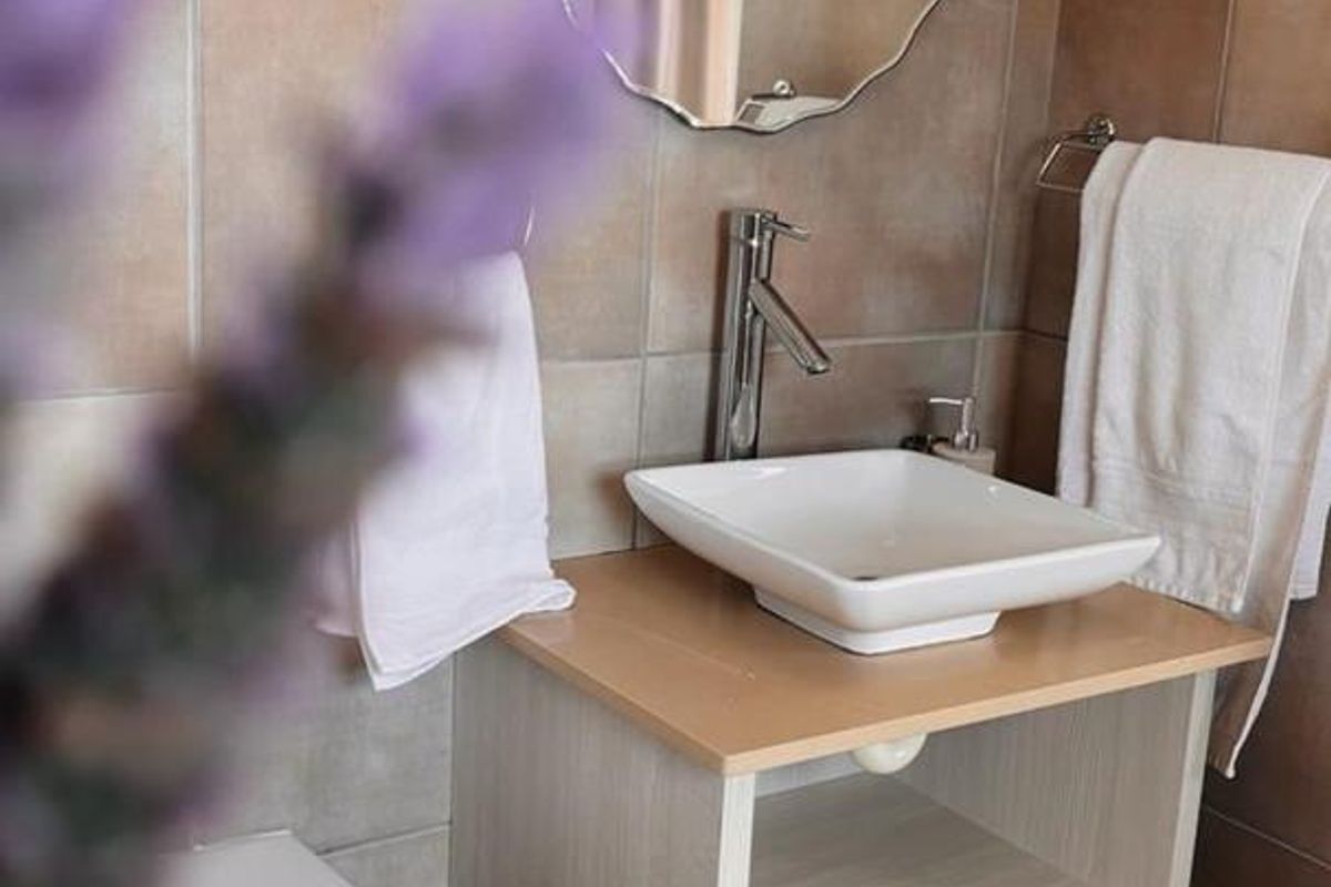 A bathroom featuring a modern vessel sink, vanity cabinet, and tiled walls with a decorative mirror.