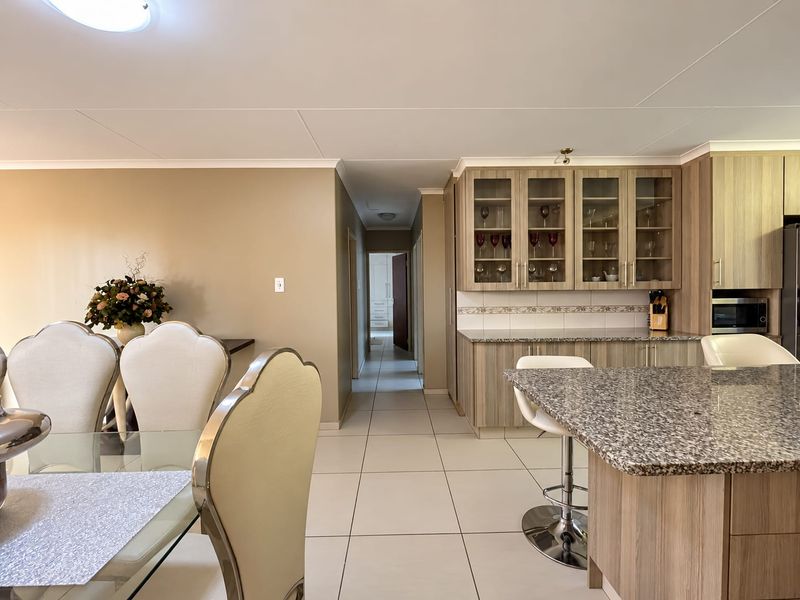 Open-plan living and dining area featuring a modern kitchen with granite countertops, ample cabinetry, and tiled flooring throughout.