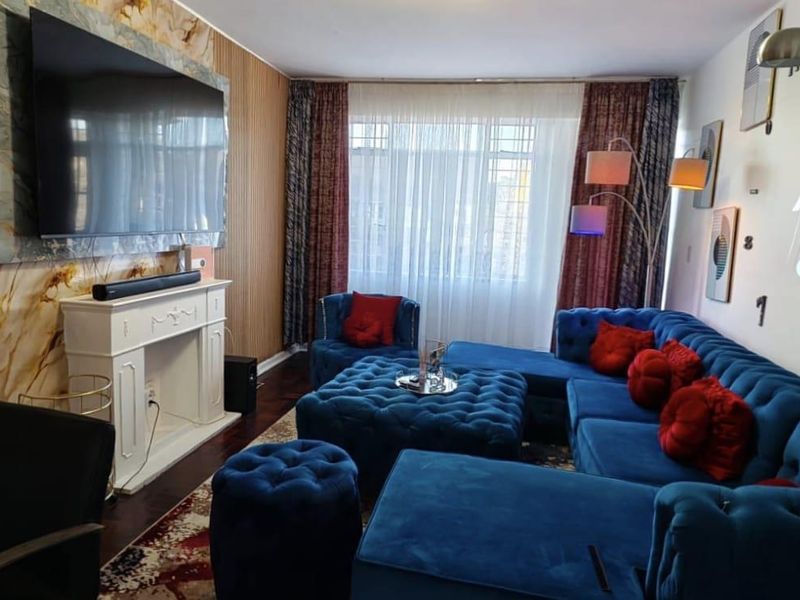 A living room featuring a decorative fireplace surround, marble-effect wall cladding, and vertical wood-style paneling, creating a distinct focal point.