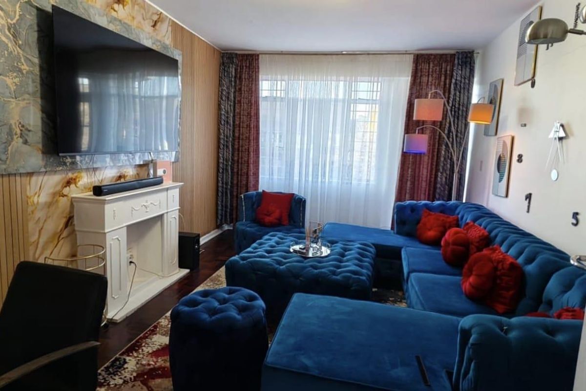 A living room featuring a decorative fireplace surround, marble-effect wall cladding, and vertical wood-style paneling, creating a distinct focal point.