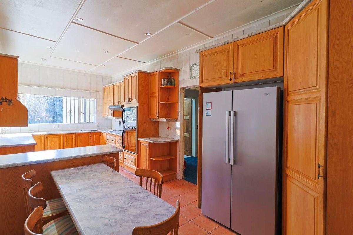 A functional kitchen featuring wooden cabinetry, laminate countertops, built-in oven, and tiled flooring, offering a traditional layout with ample storage space.