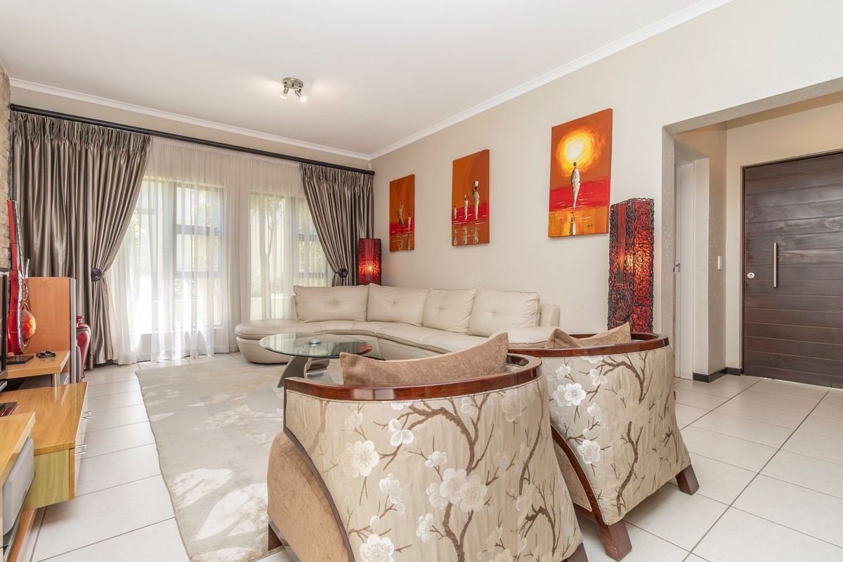 A bright and spacious living room featuring tiled flooring, large sliding glass doors for natural light, and modern recessed ceiling lighting.