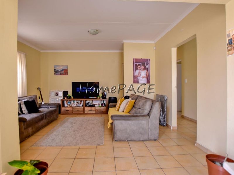 A spacious living room featuring neutral wall tones and tiled flooring, providing a functional and comfortable area for relaxation.