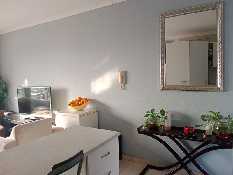 A living area featuring light blue walls, tiled flooring, and a wall-mounted intercom system.