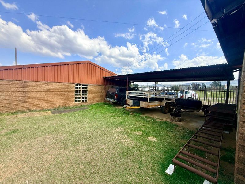 Rear exterior area featuring a covered parking structure, brick walling, and security fencing, providing functional outdoor space for the office property.