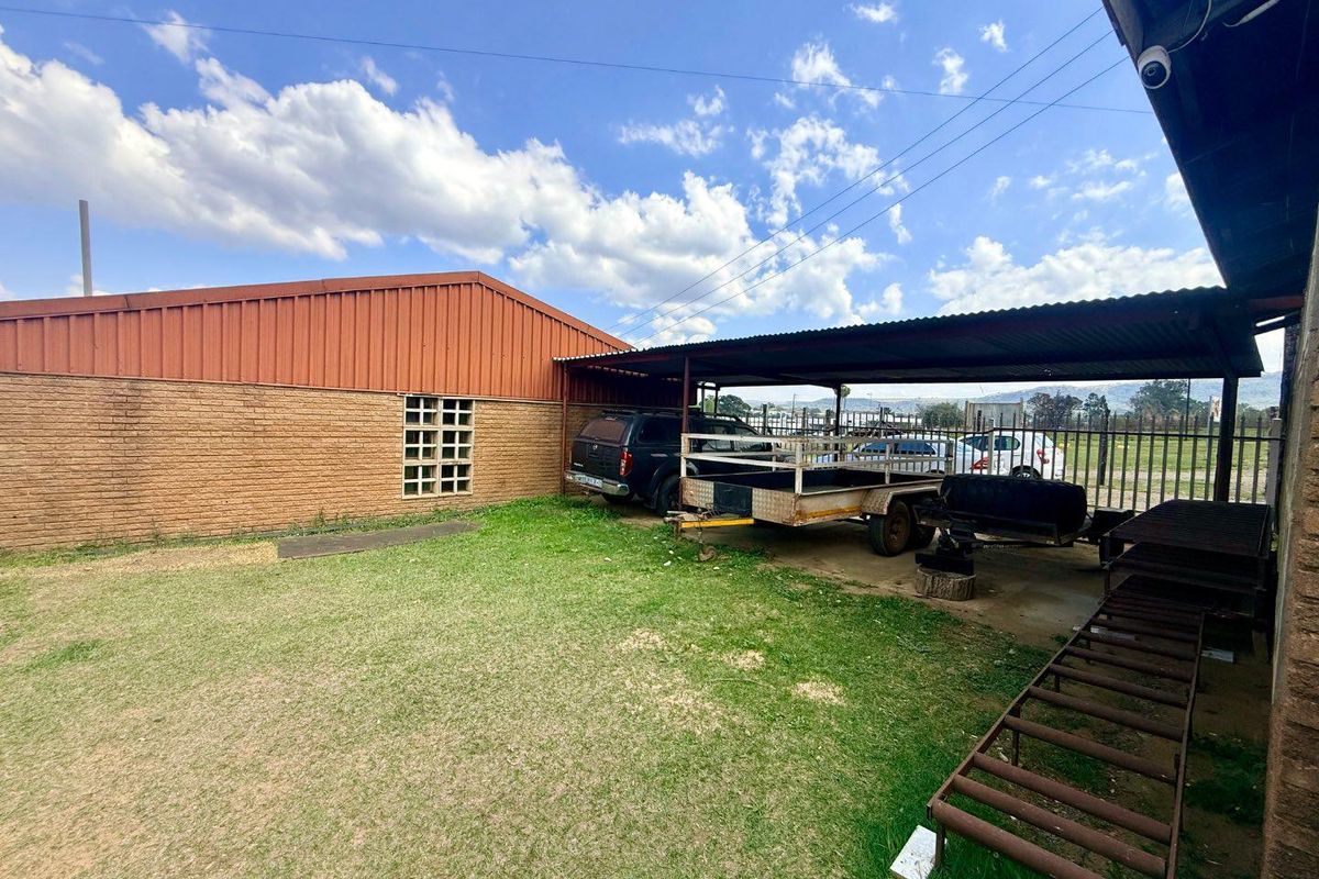 Rear exterior area featuring a covered parking structure, brick walling, and security fencing, providing functional outdoor space for the office property.