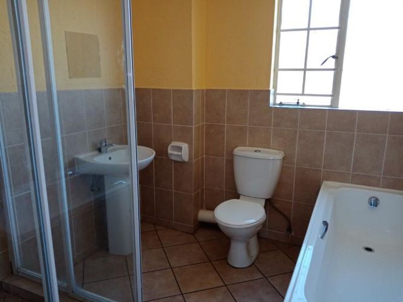 A functional bathroom featuring a pedestal basin, toilet, bathtub, and a separate shower enclosure with tiled finishes throughout.