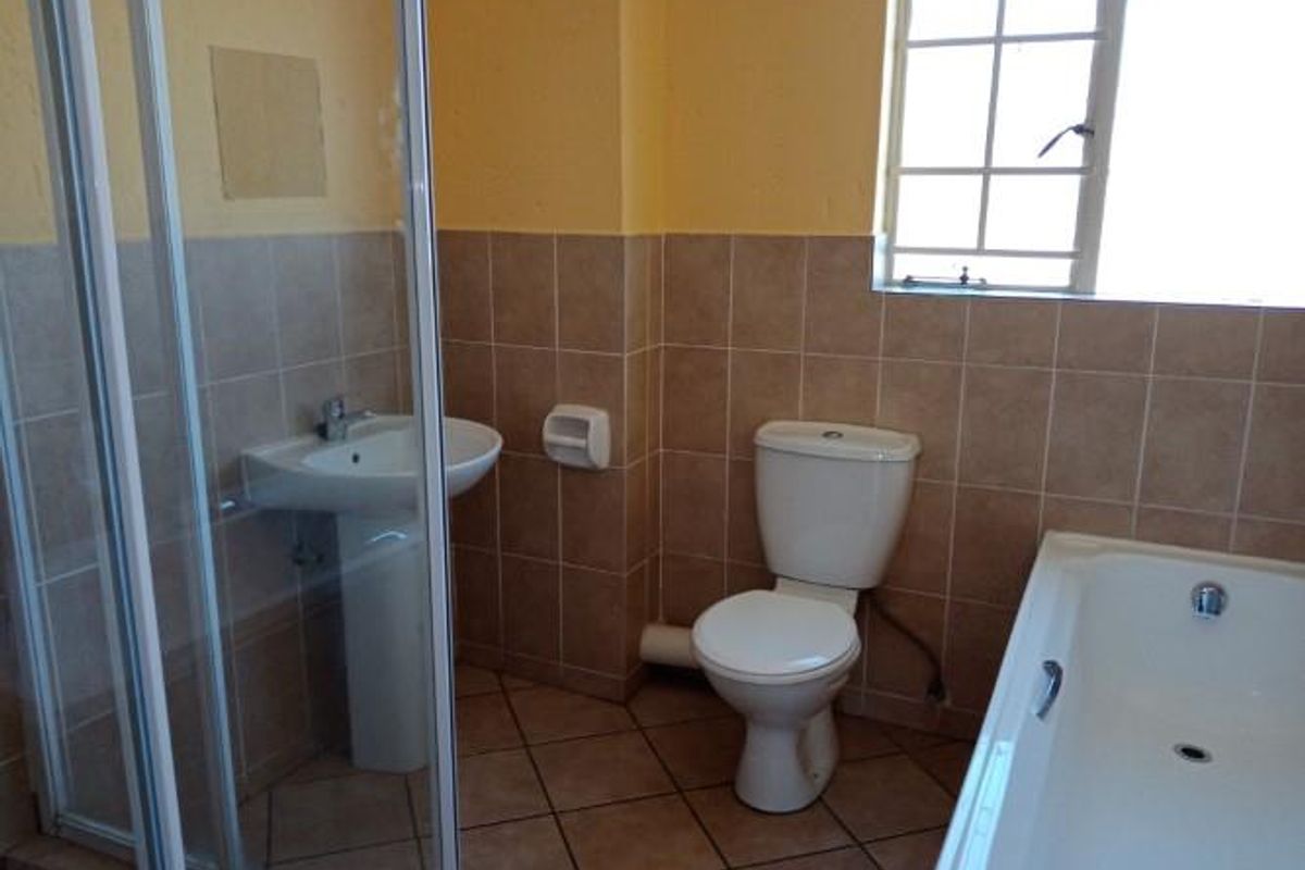 A functional bathroom featuring a pedestal basin, toilet, bathtub, and a separate shower enclosure with tiled finishes throughout.
