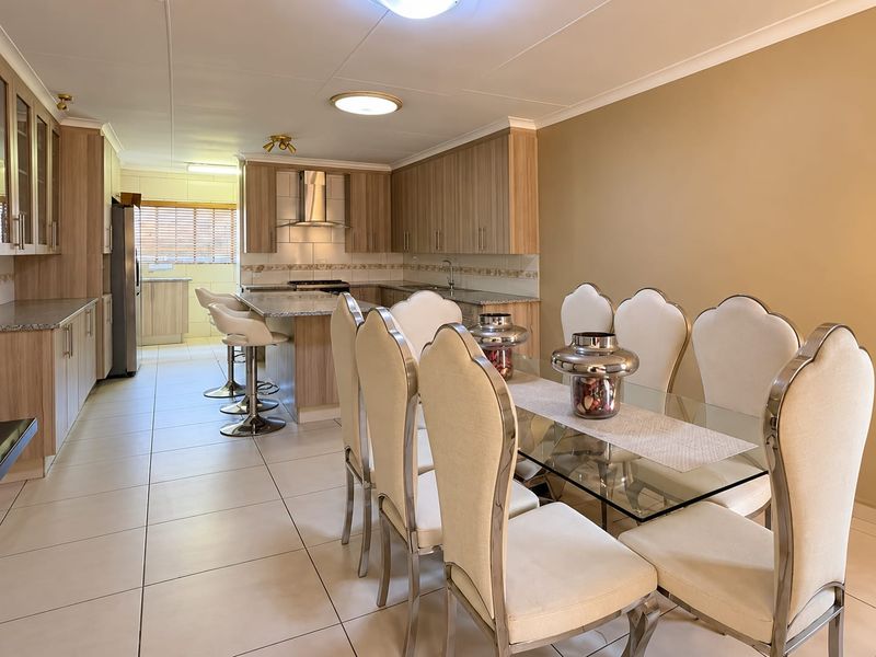 Spacious open-plan kitchen and dining area featuring modern wood-finish cabinetry, granite countertops, and tiled flooring throughout.