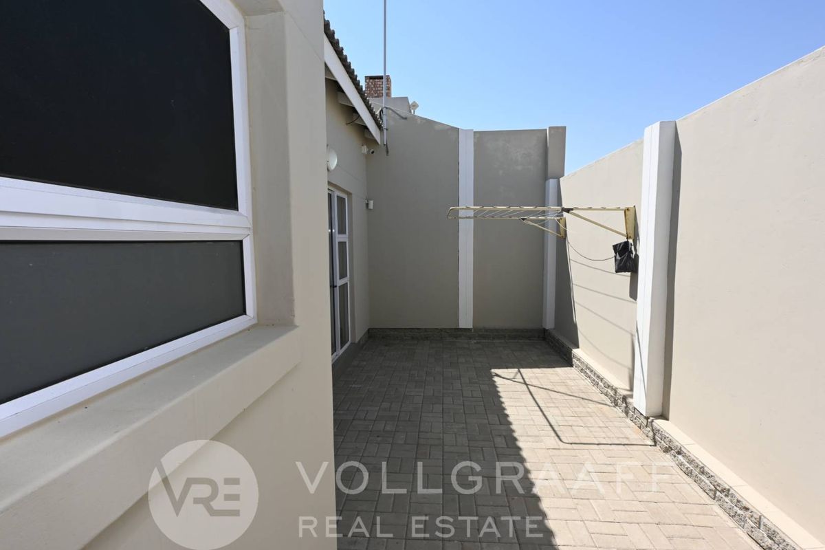 A private paved courtyard area featuring high boundary walls and a wall-mounted drying rack, providing a secure and low-maintenance outdoor space.