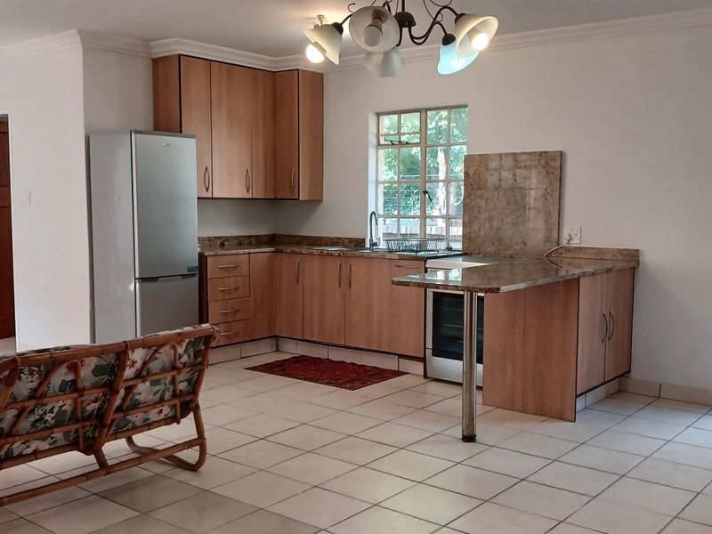 Open-plan kitchen featuring laminate cabinetry, granite countertops, and tiled flooring, seamlessly connected to the living area with direct access to the exterior.