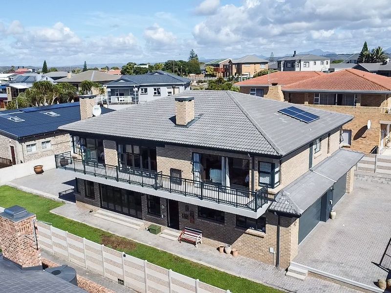 Aerial view of a two-story brick house featuring a tiled roof with solar panels, a balcony with metal railings, and a paved driveway.