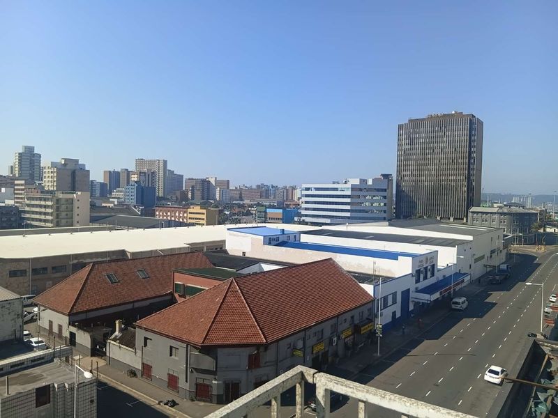 Elevated urban cityscape view overlooking surrounding commercial buildings and street infrastructure from a balcony perspective.