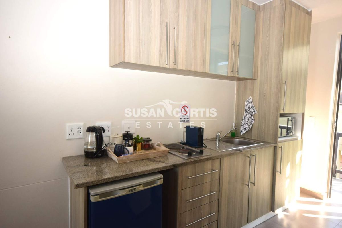 Compact kitchenette featuring modern laminate cabinetry, granite countertops, a stainless steel sink, and a built-in hob and microwave.