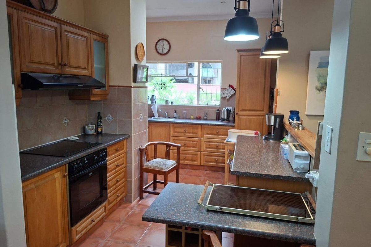 A traditional kitchen featuring wooden cabinetry, tiled flooring, a built-in oven and hob, and a breakfast bar counter.
