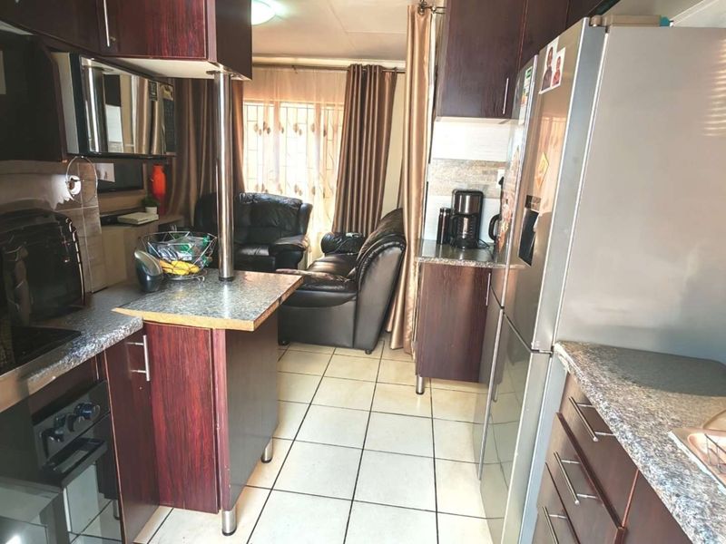 Open plan kitchen and living area featuring dark wood cabinetry, laminate countertops, and ceramic floor tiles.