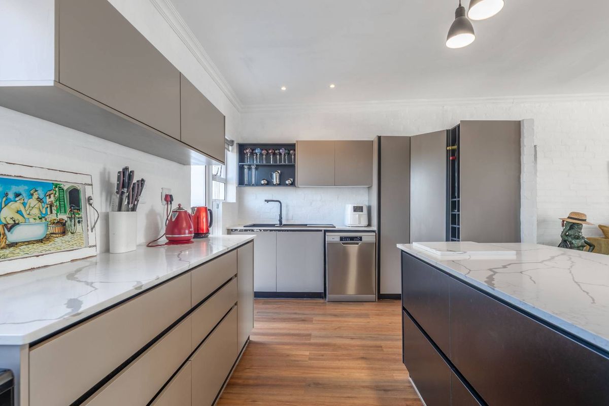 Modern kitchen featuring sleek cabinetry, stone countertops, a central island, and integrated appliances, offering a clean and contemporary culinary space.