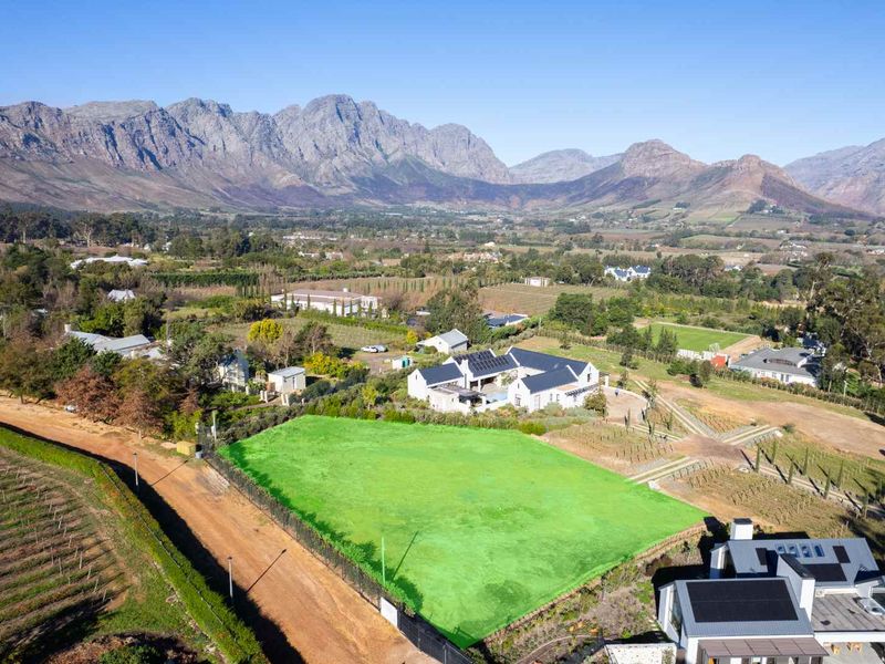An aerial view of a vacant residential plot featuring clear boundaries, set within a scenic landscape with mountain views.
