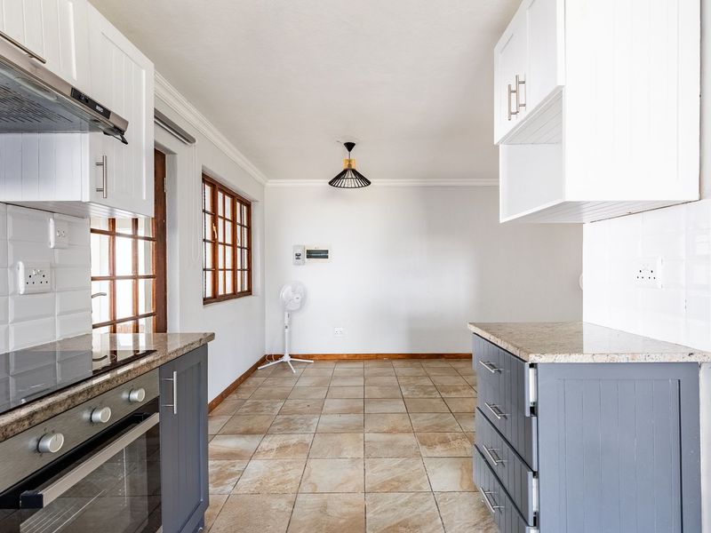 A functional kitchen featuring granite countertops, built-in oven, extractor fan, and tiled flooring, offering a clean and practical layout for culinary activities.